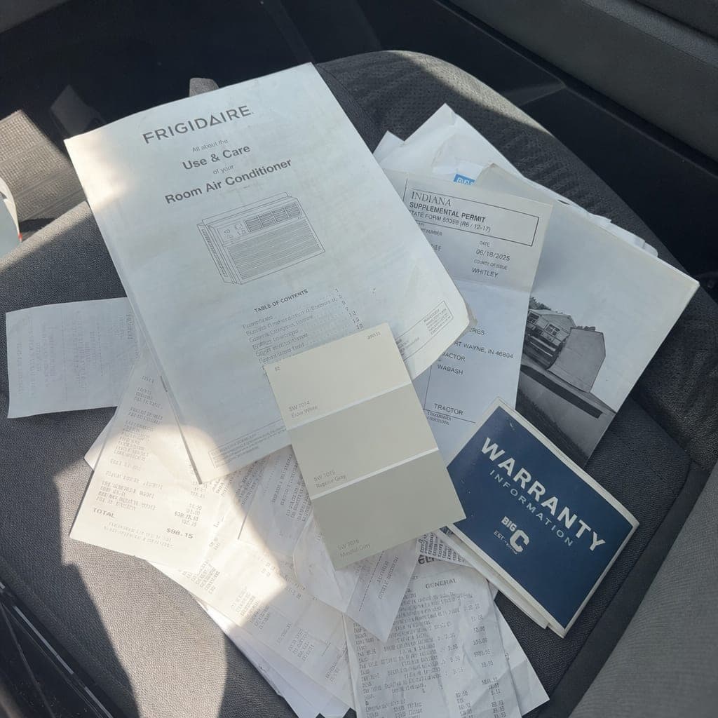A pile of receipts, manuals, a permit card and a paint chip on a truck seat